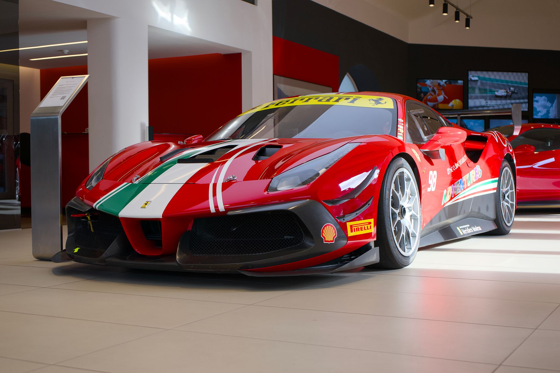 Czerwone Ferrari z rajdowymi naklejkami w salonie samochodowym