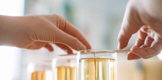 Dłonie ręcznie nalewające naturalne świece sojowe do szklanych naczyń