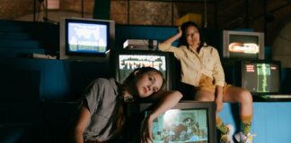 Dwie kobiety grające na retro konsolach przy starych telewizorach