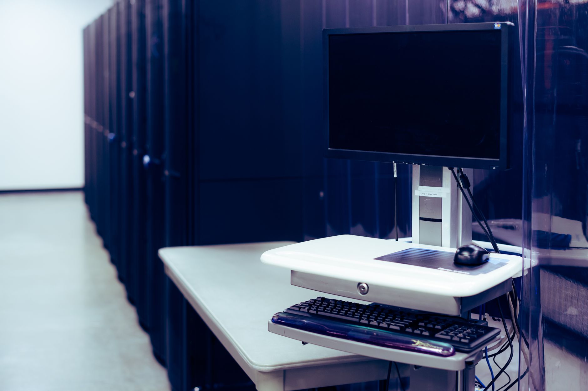 Komputer z czarnym ekranem na tle rzędów serwerów w data center