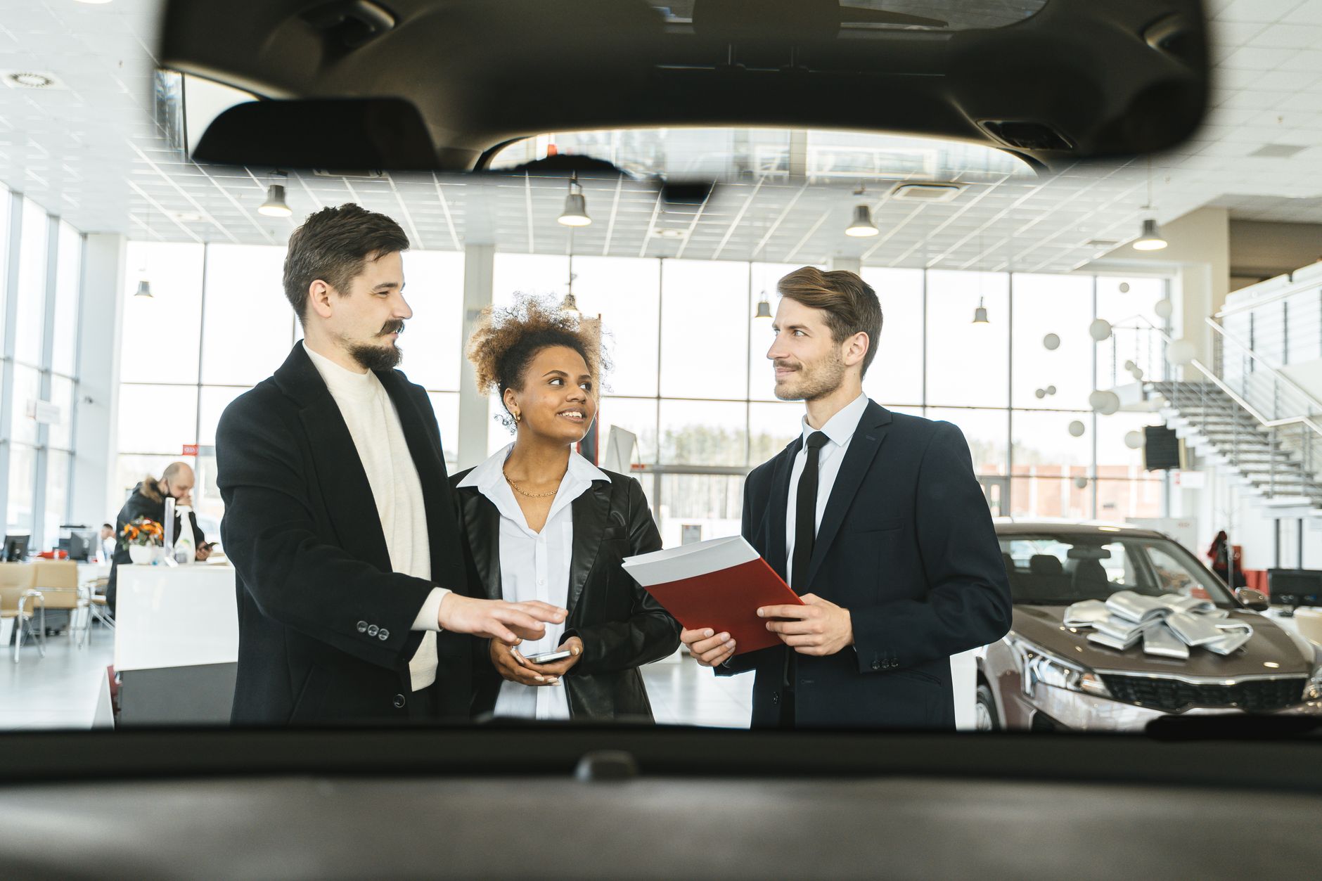 Trzy osoby w salonie dyskutują o zakupie firmowego Volvo