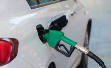 Zielony dystrybutor tankujący białego Volkswagena na stacji paliw