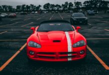 Czerwone Ferrari zaparkowane na pustym parkingu pod zachmurzonym niebem