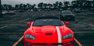 Czerwone Ferrari zaparkowane na pustym parkingu pod zachmurzonym niebem