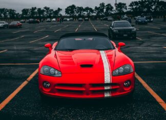 Czerwone Ferrari zaparkowane na pustym parkingu pod zachmurzonym niebem