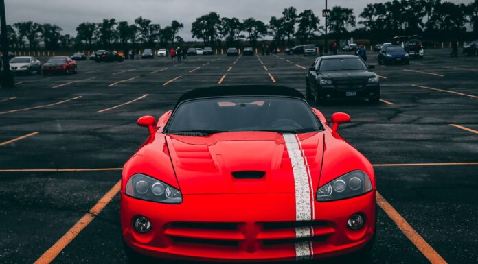 Czerwone Ferrari zaparkowane na pustym parkingu pod zachmurzonym niebem