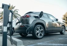 Nowoczesny Jeep plug-in hybrid podłączony do ładowarki na zewnątrz