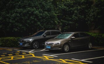 SUV i sedan zaparkowane obok siebie na zacienionym parkingu miejskim